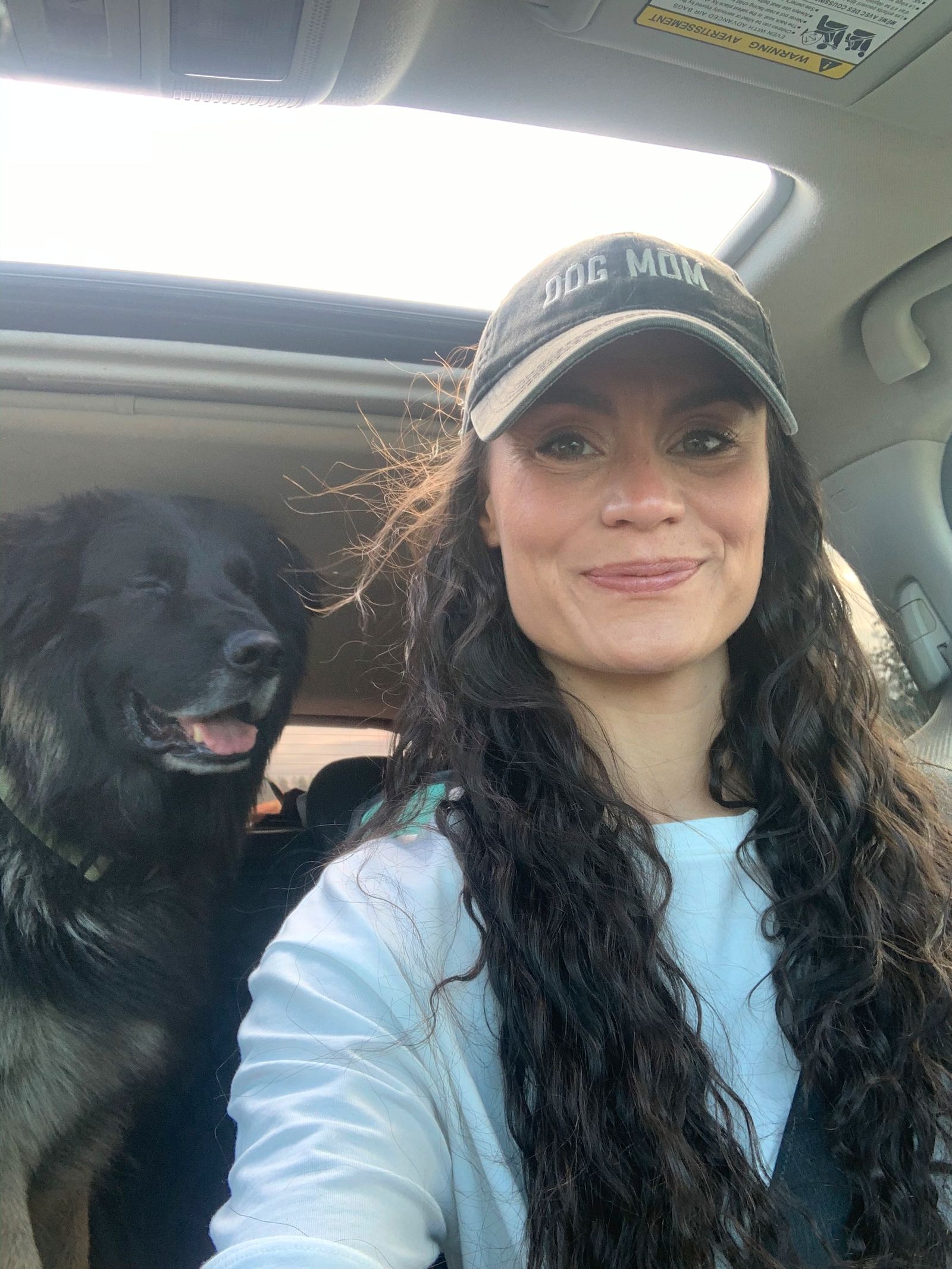 Shayla smilling and dog beside her inside her car