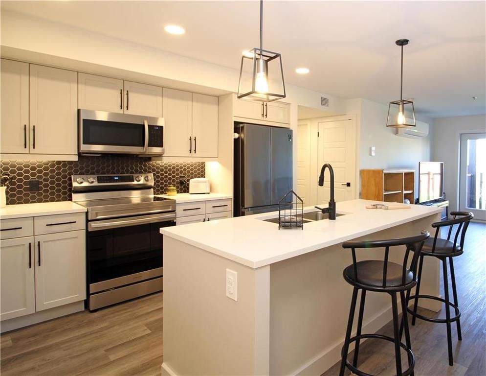Well appointed kitchen with quartz countertops, black tile backsplash, high end SS appliances,  beautiful pendant and pot lighting and a large island that can seat up to four.