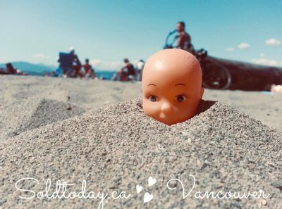 Kitsilano Beach in Vancouver Summer. Toy head pop out from the sand.